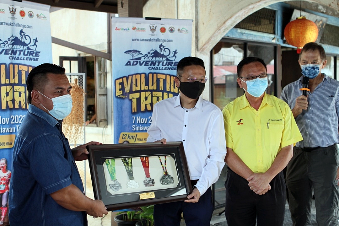Serembu assemblyman Miro Simuh (left) receives a souvenir from co-race director Chua Juan Chuan after the launch of the 5th SAC on Friday at Ayak Gallery, Siniawan Bazaar as Batu Kitang state assemblyman Lo Khere Chiang (second right) and co-race director Robert Basiuk look on.